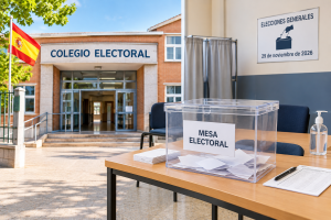 Colegio electoral y mesa electoral con urna transparente y papeletas para votar en las Elecciones Generales en España.